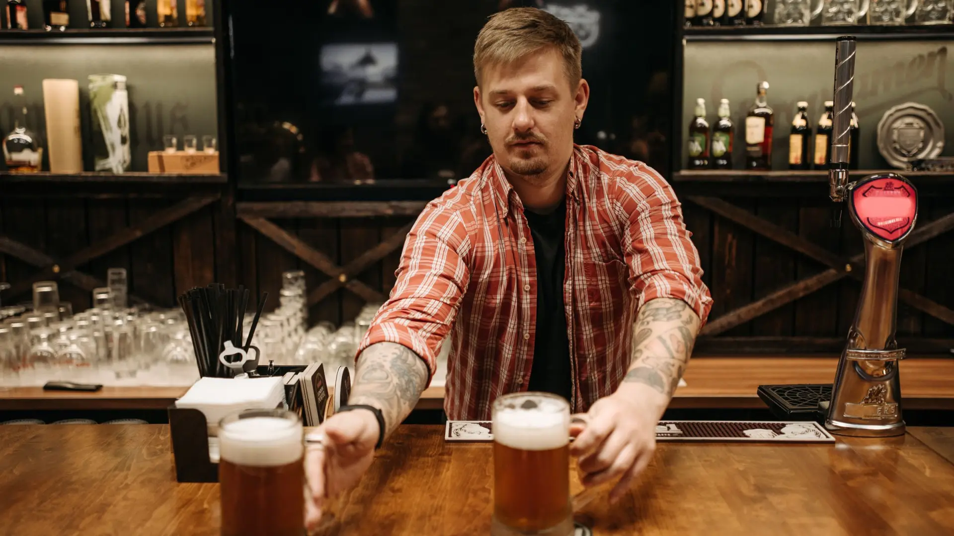 A landlord setting down two pints at the bar